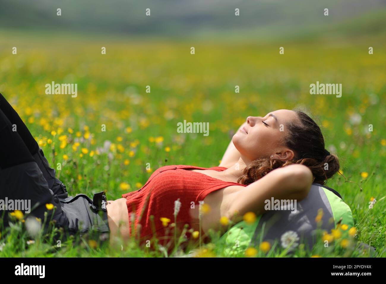 Backpacker rilassarsi sdraiandosi sull'erba in mezzo alla natura Foto Stock