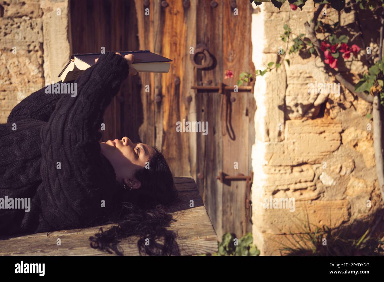 giovane donna latina in giardino che legge un libro Foto Stock