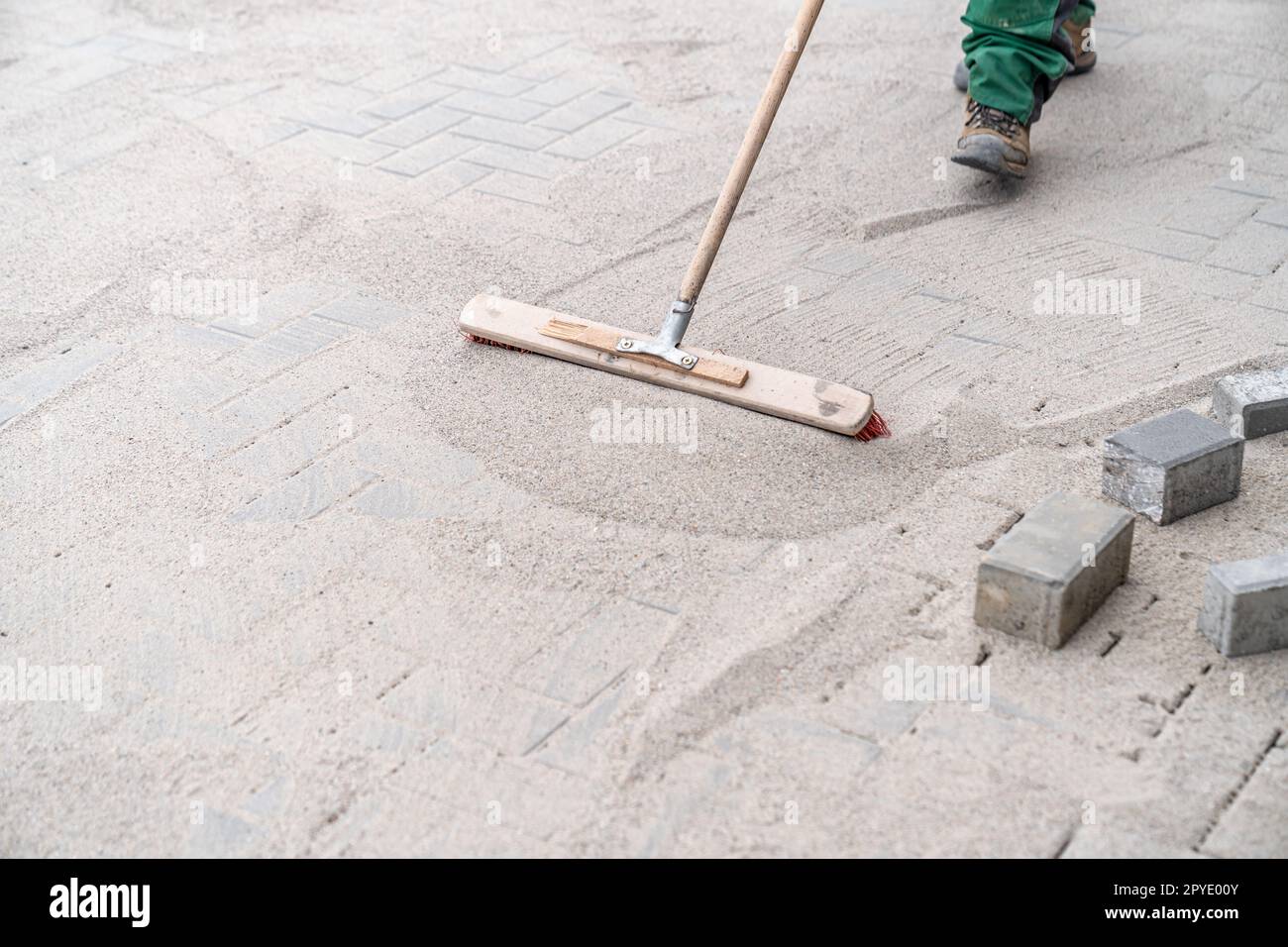 sabbia spazzante sul nuovo marciapiede Foto Stock