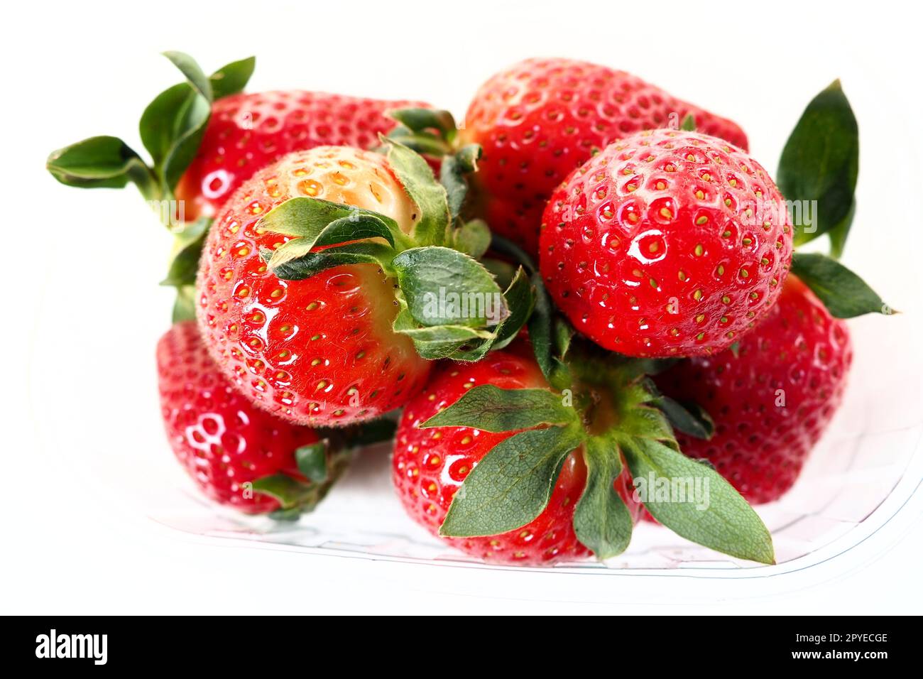 Fragole mature in una confezione di plastica su sfondo bianco. Deliziose bacche fresche in un contenitore per la vendita ai clienti. Mantenere il cibo fresco. Cibo sano, vitamine e microelementi. Foto Stock