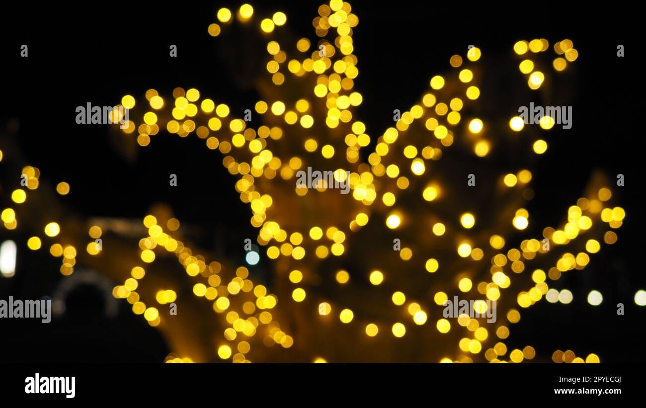 Bokeh la sera di Natale. Bellissimi dettagli bokeh rotondi. I colori oro e giallo lampeggiano al buio. Sfondo natalizio per Capodanno buon Natale. Sfocatura sfocata. Decorazione delle strade cittadine. Foto Stock