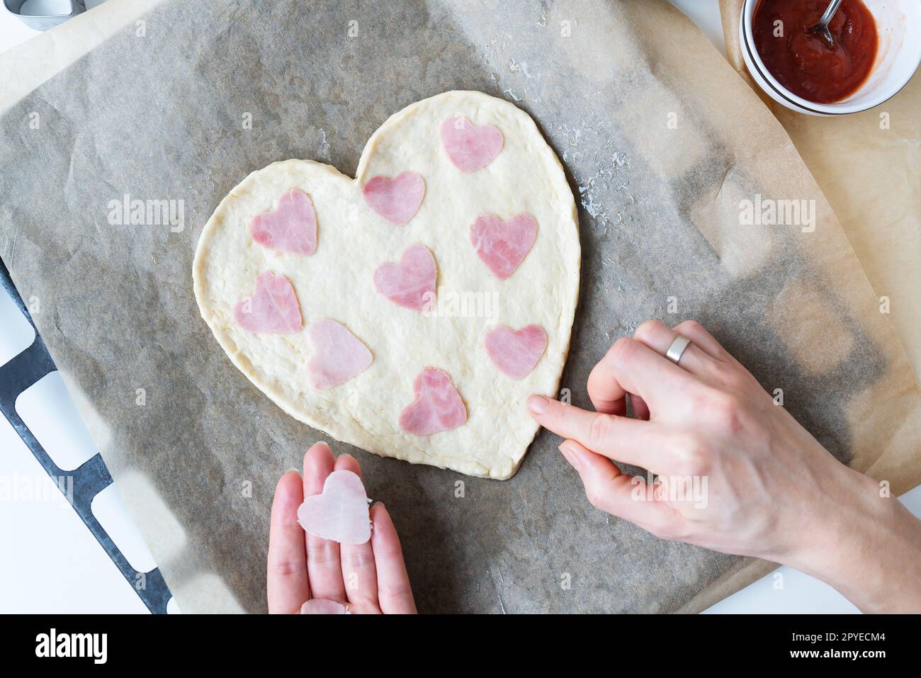 Impasto per pizza a forma di cuore, lo chef prepara salsicce a forma di cuore. Pizza italiana, pizza a forma di cuore. Foto Stock
