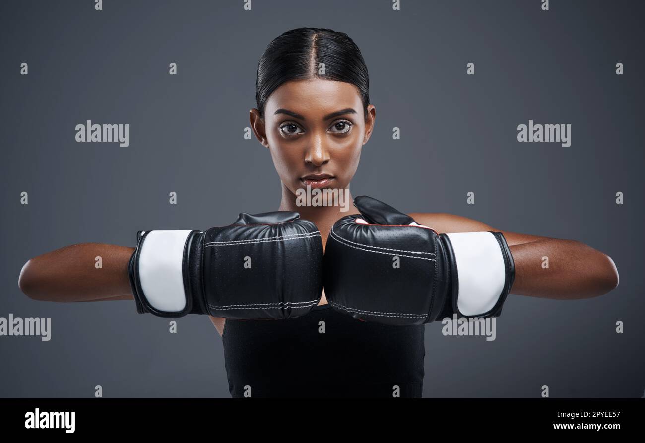 Entra nell'anello e Ill ti mostra la mia forza. Studio ritratto di una giovane donna sportiva che indossa guanti da boxe su sfondo grigio. Foto Stock