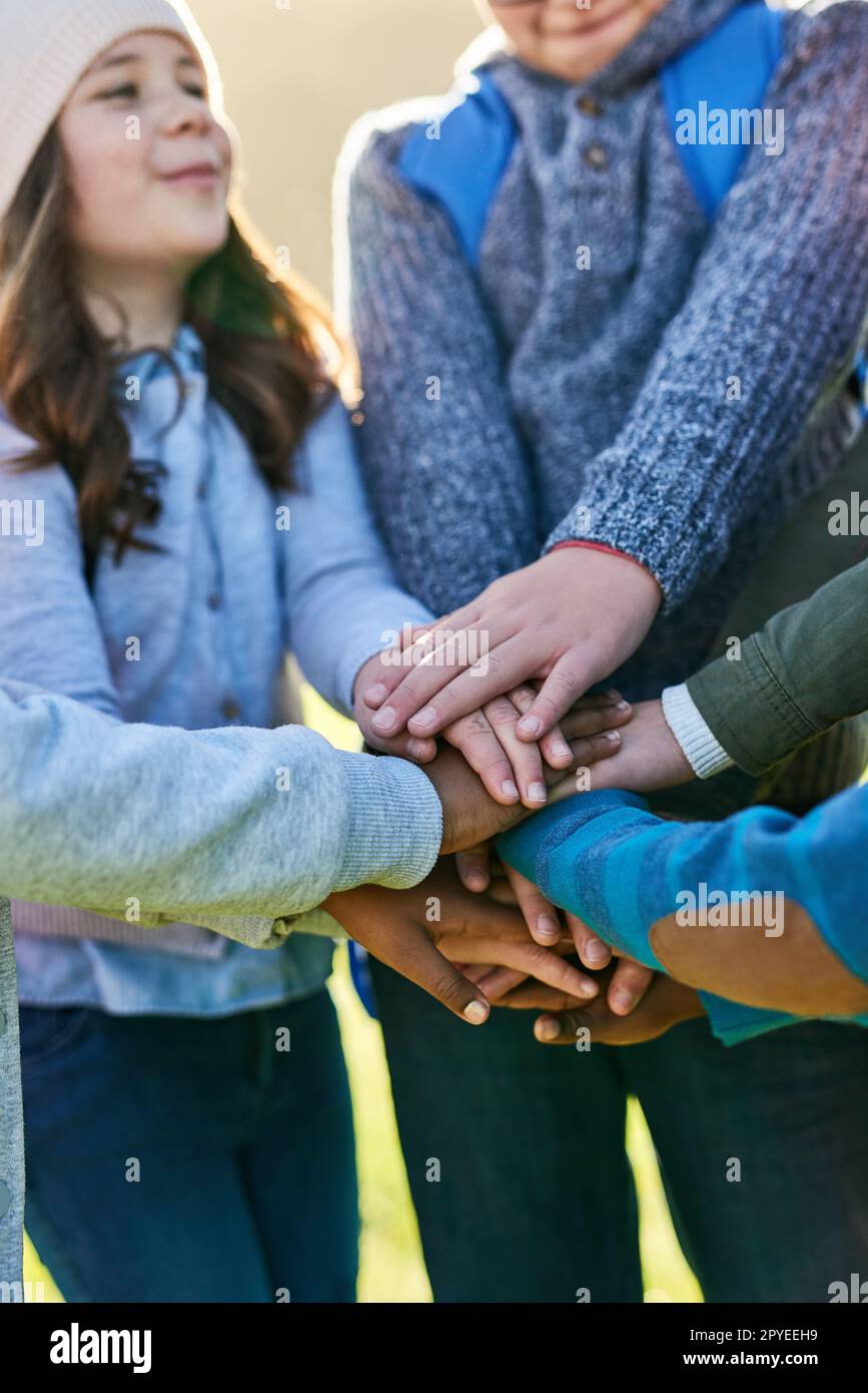 I bambini si uniscono. un gruppo di ragazzi irriconoscibili della scuola elementare che si uniscono le mani in un huddle all'esterno. Foto Stock
