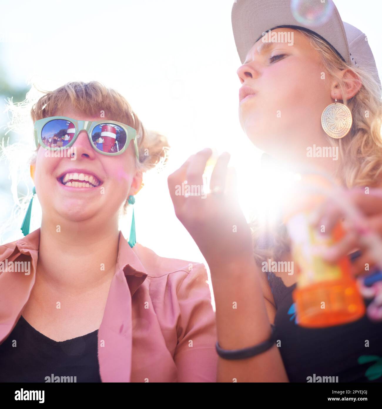 Godendo del lato più leggero della vita. una donna che soffia bolle fuori mentre il suo amico sorride accanto a lei. Foto Stock