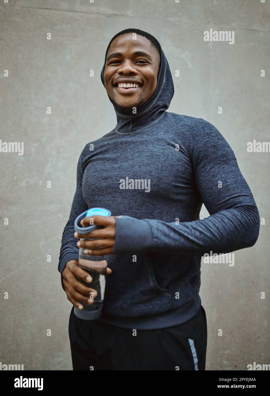 Uomo nero corridore, felice e ritratto per muro, città e bottiglia d'acqua per la salute, il fitness o il benessere. Uomo urbano, sorriso e felicità per correre, allenarsi o allenarsi in metropolitana con cura personale a Chicago Foto Stock