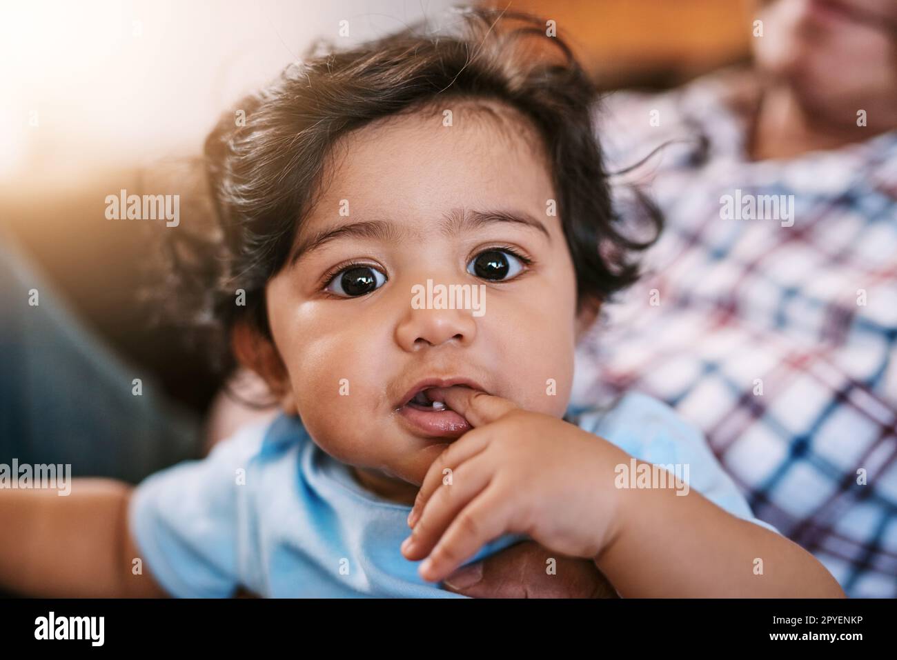 Essere molto curioso. Ritratto di un allegro bambino seduto sul suo giro dads mentre guarda la macchina fotografica a casa durante il giorno. Foto Stock