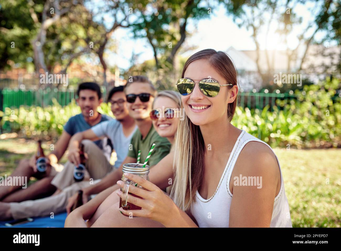 E' questo il tema dell'estate. Ritratto corto di una giovane donna attraente godendo un paio di bevande con gli amici fuori nel sole estivo. Foto Stock