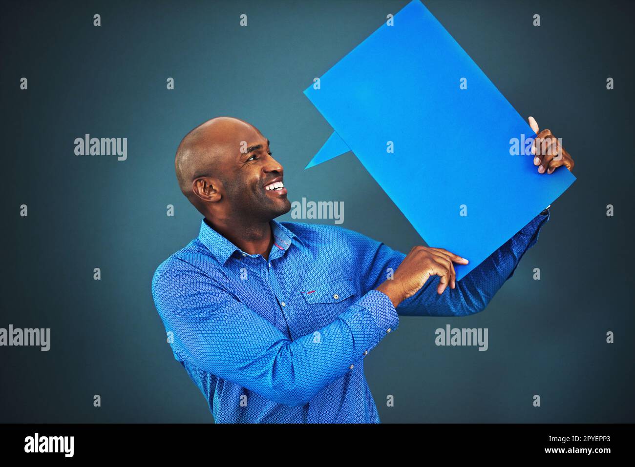 Parla. Studio di un uomo che tiene una bolla di discorso su uno sfondo blu. Foto Stock