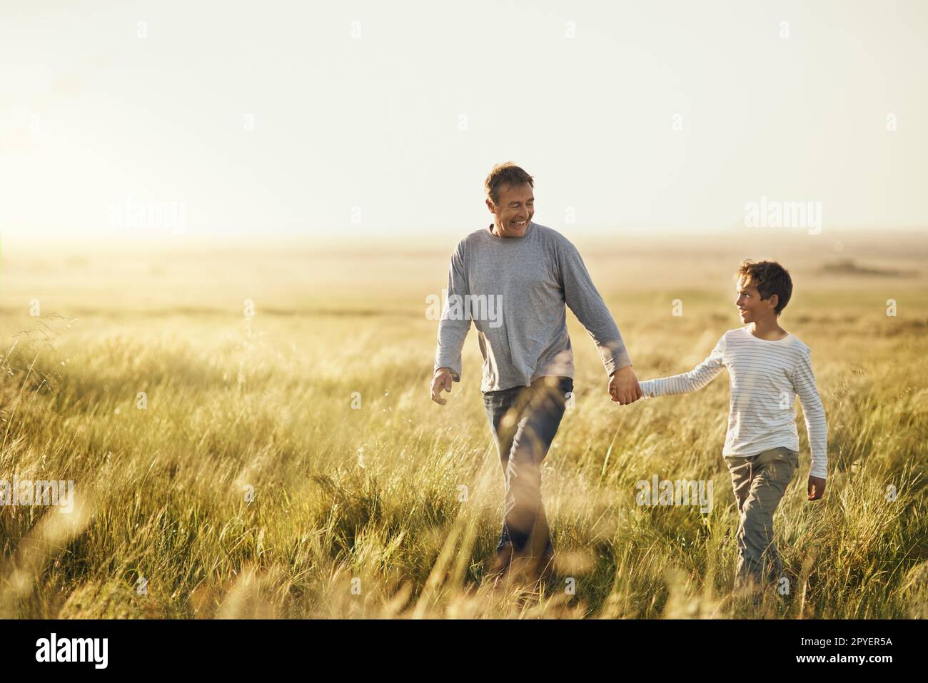 In un'avventura. un uomo che porta suo figlio per una passeggiata su un campo aperto. Foto Stock