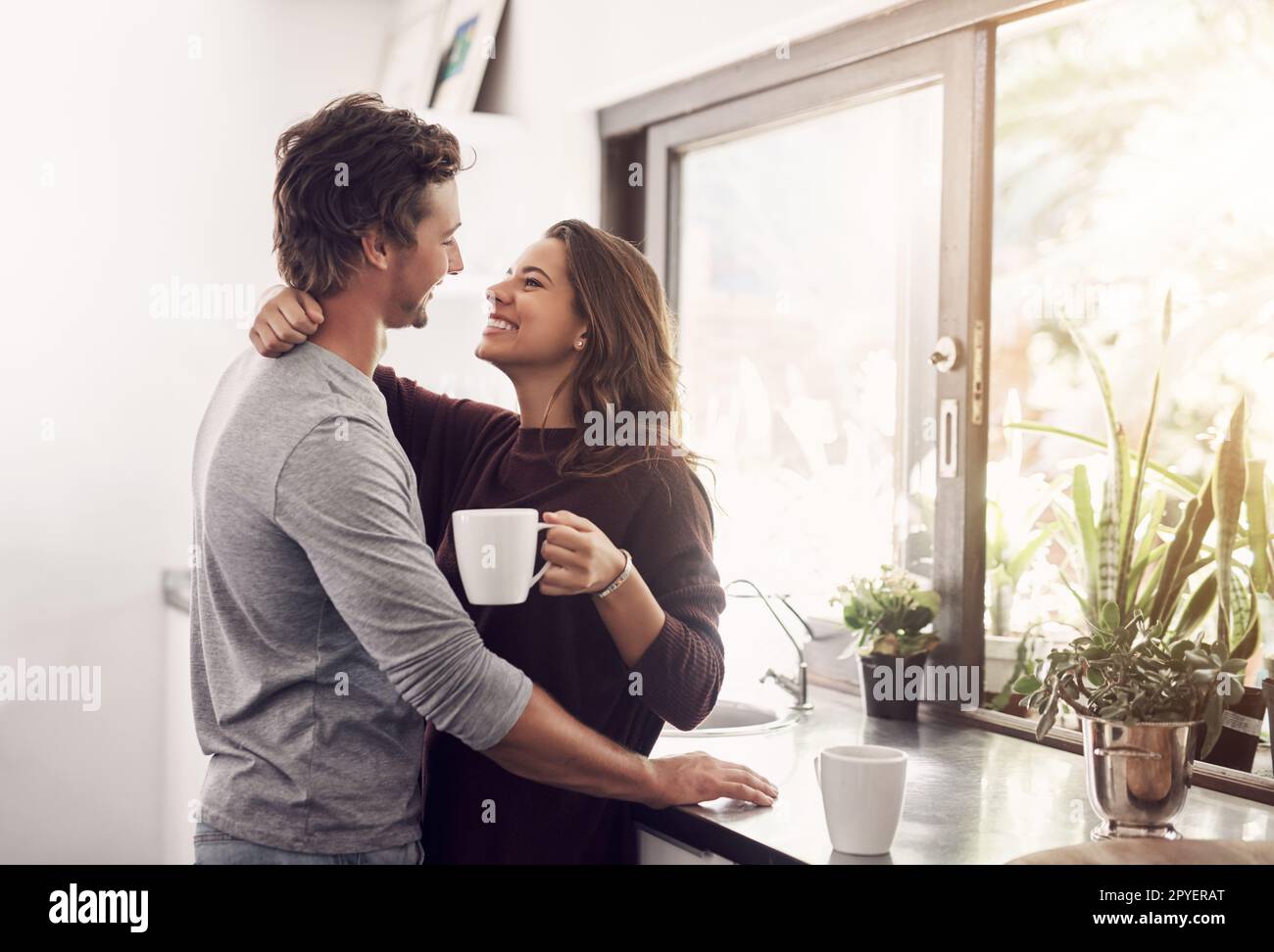 La mattina insieme rende la giornata ancora migliore. una giovane coppia affettuosa che ha una pausa caffè a casa. Foto Stock