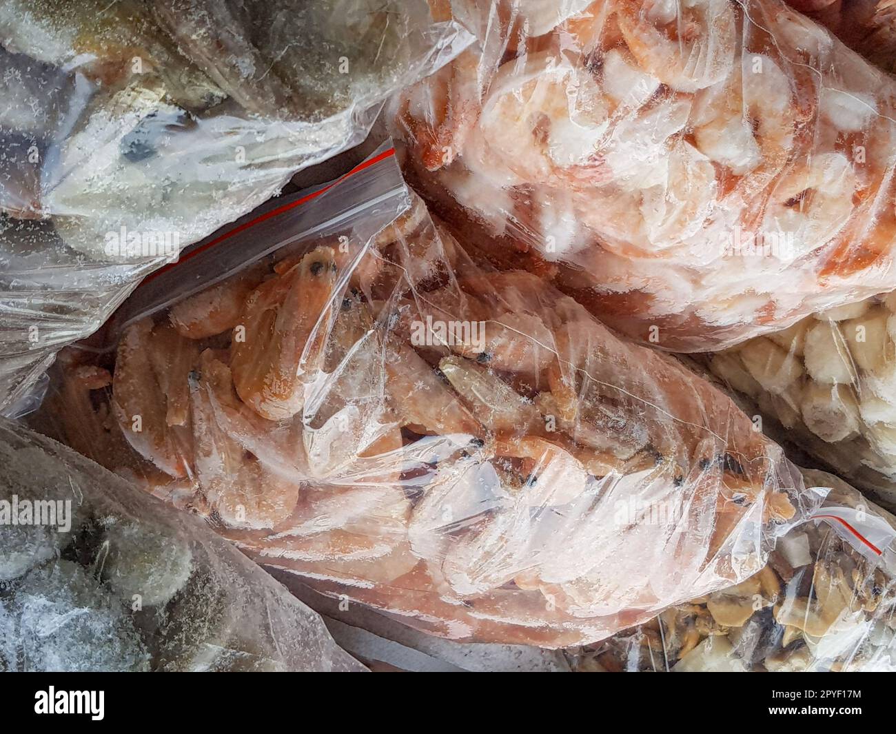 Ci sono molti grandi sacchetti di plastica con i gamberetti surgelati crudi e bolliti sul banco del mercato del pesce. Foto Stock