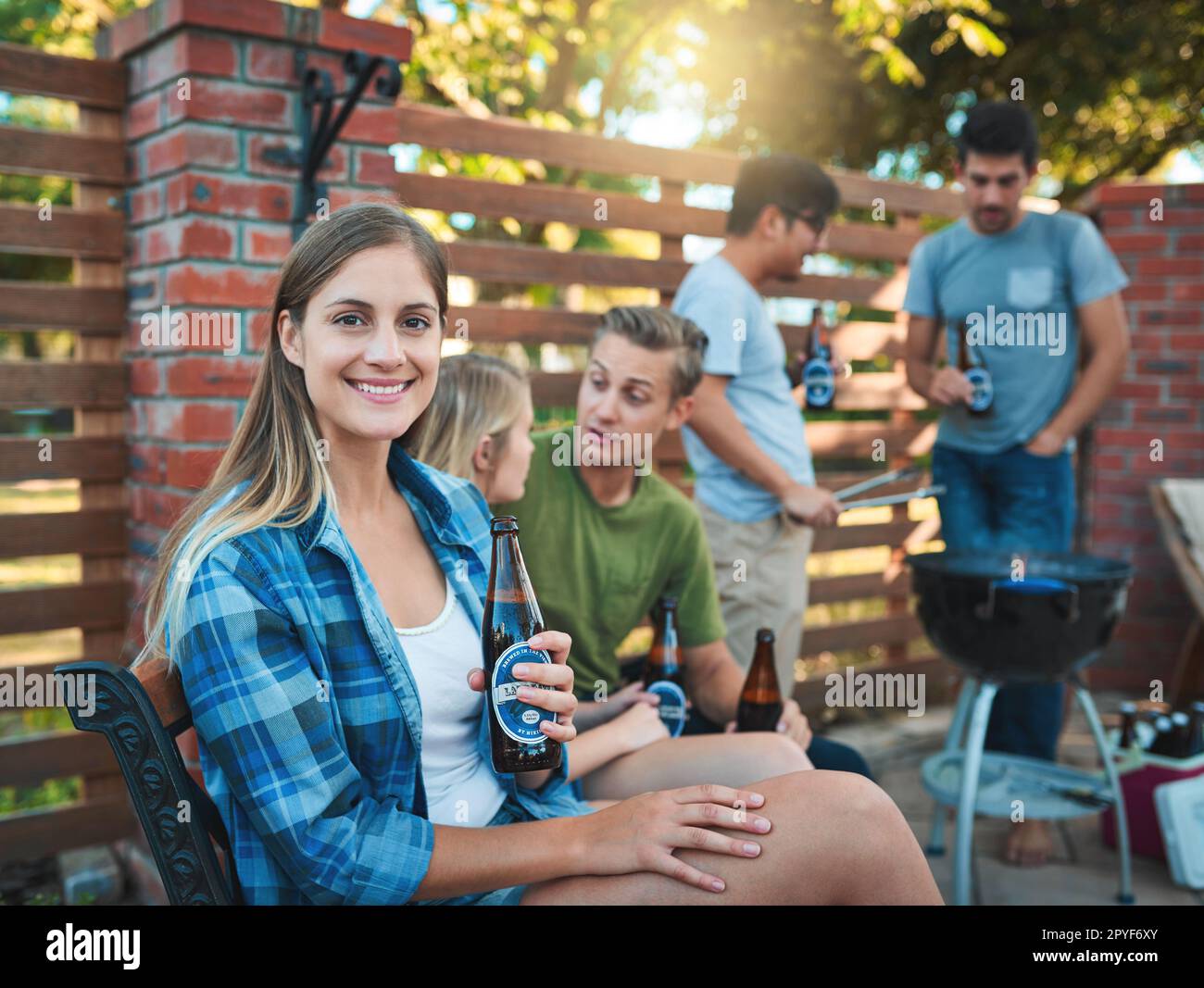 Momenti di divertimento con alcuni dei miei preferiti. una giovane donna felice che gustava una birra al barbecue con i suoi amici. Foto Stock
