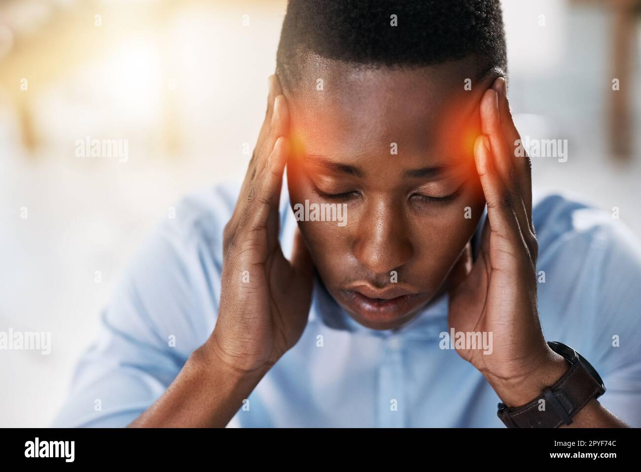 Speriamo che questo mal di testa andrà via presto. un uomo d'affari giovane e stressato che soffre di mal di testa mentre cerca di lavorare in ufficio. Foto Stock