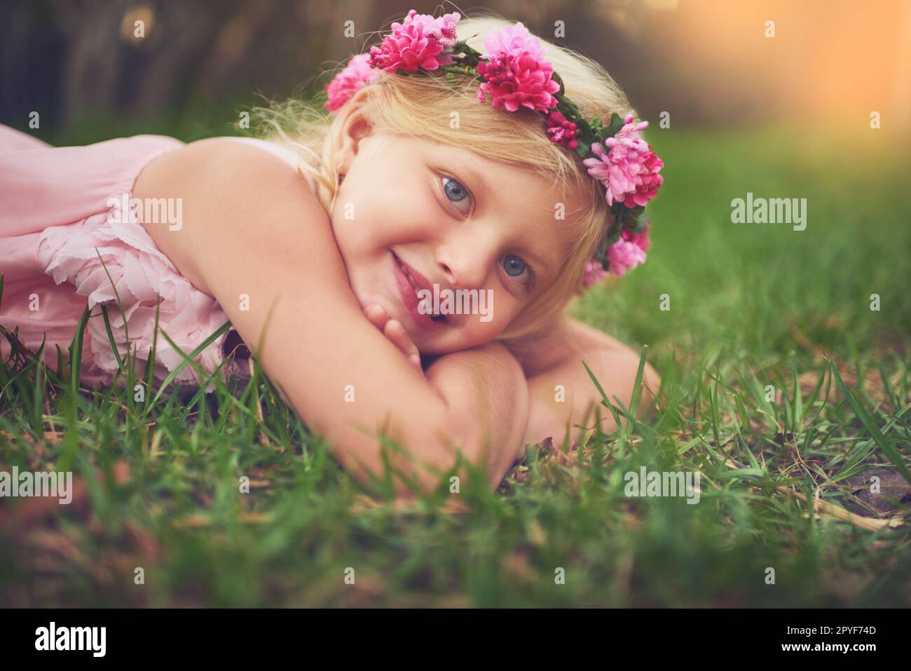 Shes in connessione con la natura. una bambina felice guardando la macchina fotografica mentre sdraiata sul terreno all'esterno in natura. Foto Stock