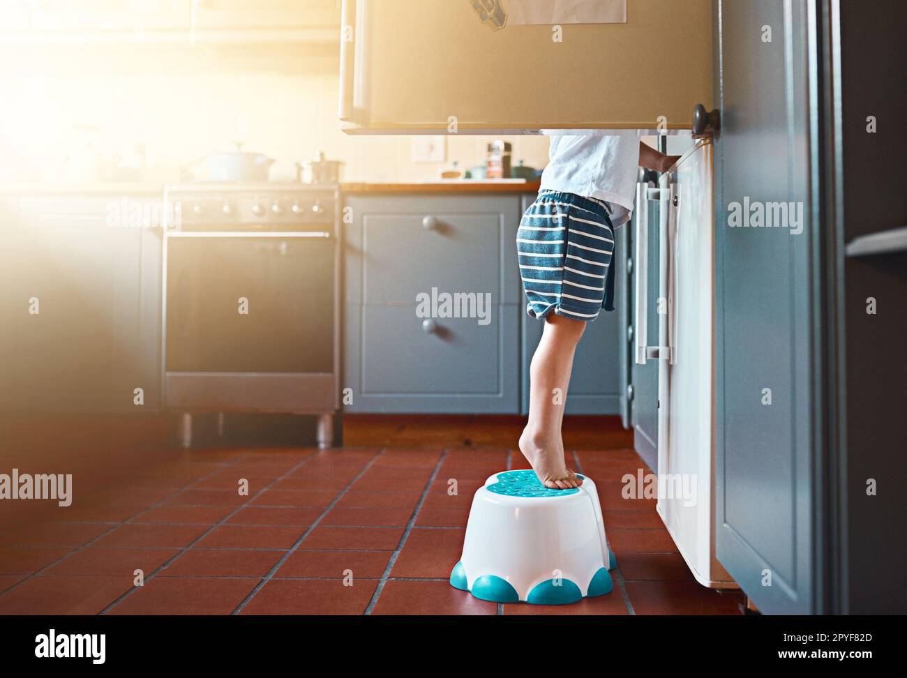 Crescere e imparare a fare il proprio cibo. un ragazzino irriconoscibile che guarda nel frigorifero di casa. Foto Stock