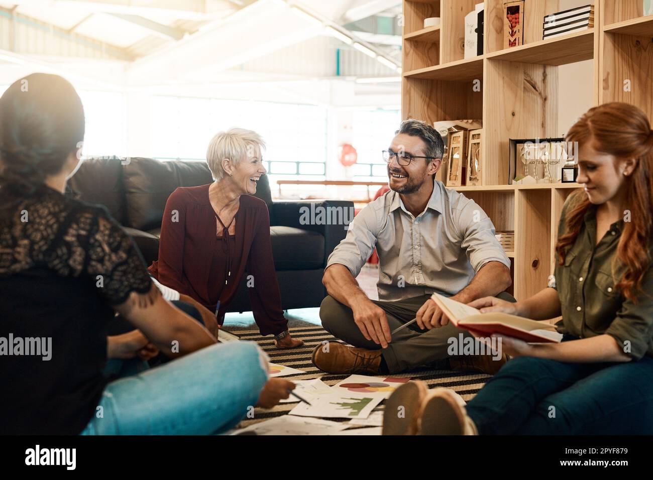 Pensiamo diversamente. un gruppo di uomini d'affari che hanno una sessione di brainstorming mentre sono seduti sul pavimento. Foto Stock