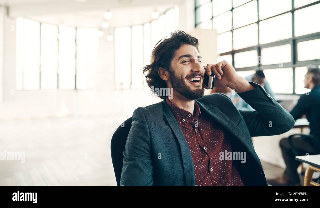 Prendersi cura degli affari con una sola chiamata. un giovane uomo d'affari che usa un cellulare in un ufficio moderno. Foto Stock