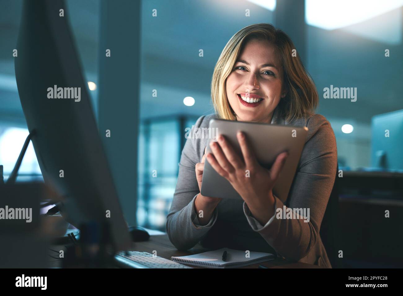 La tecnologia è necessaria fino a tarda notte. Ritratto di una giovane donna d'affari che lavora tardi su un tablet digitale in un ufficio. Foto Stock