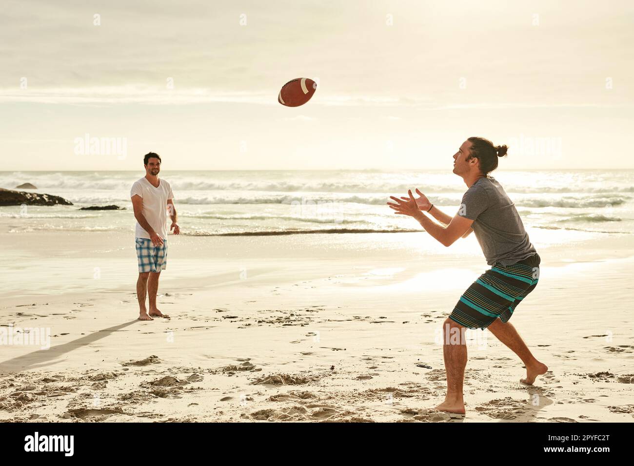 Niente di meglio di una partita di palla sulla spiaggia. due giovani amici felici che giocano con una palla sulla spiaggia. Foto Stock