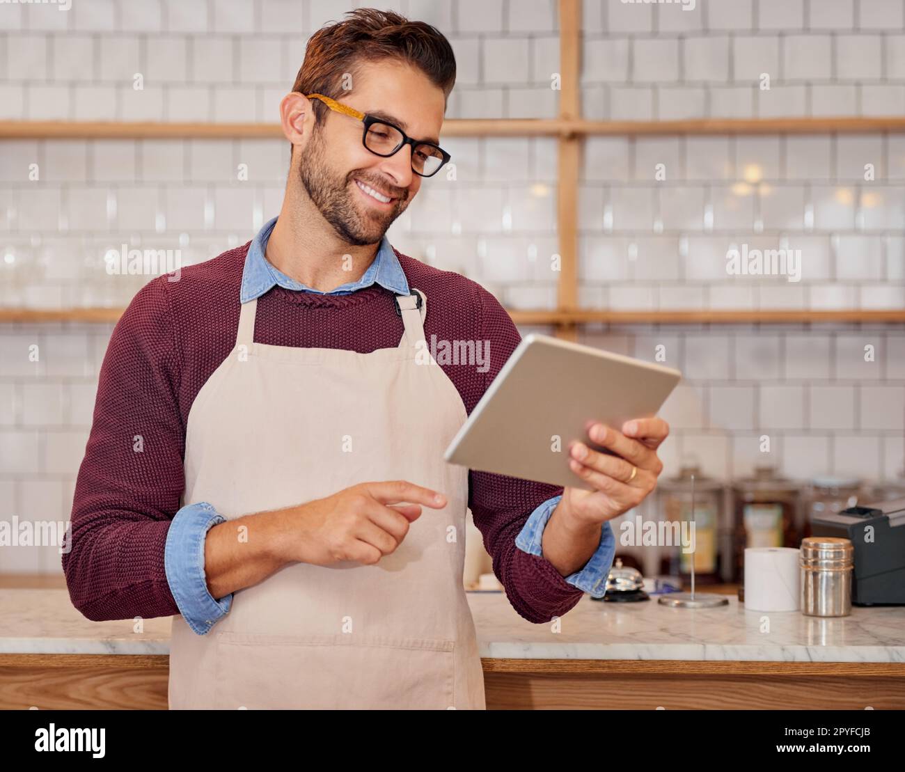 I miei clienti scrivono i commenti più belli. un giovane e felice imprenditore che utilizza un tablet mentre si trova nella sua caffetteria. Foto Stock