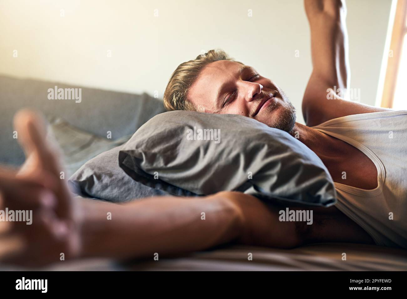 Sveglia con un Buongiorno. un giovane che si allunga mentre si sveglia a letto. Foto Stock