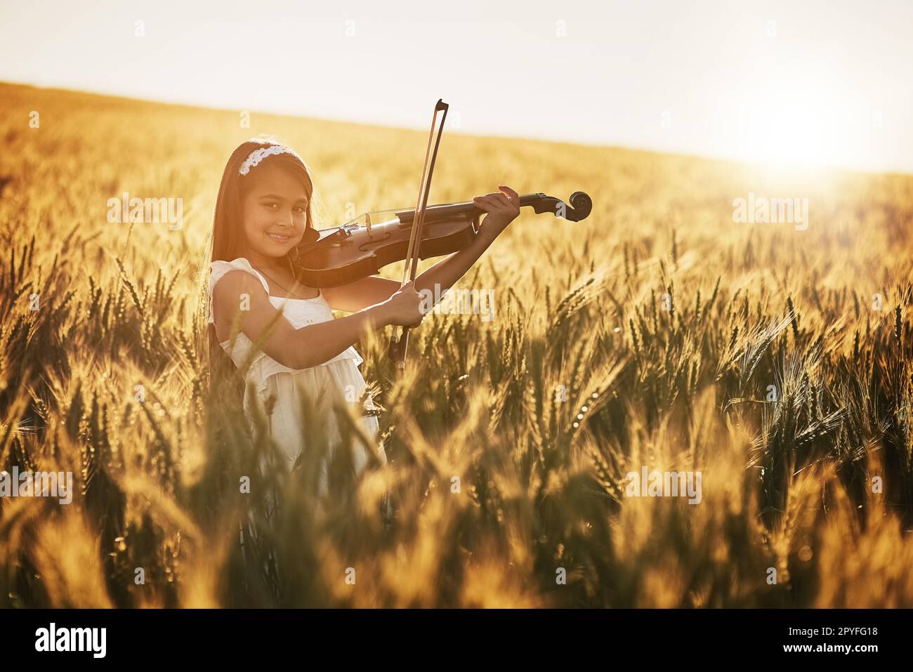 Natura piccolo maestro. Ritratto di una ragazza carina che suona il violino mentre si trova in un campo di grano. Foto Stock