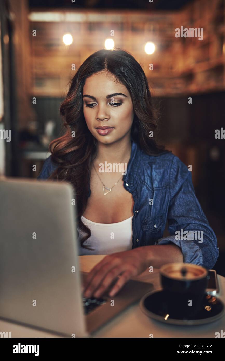 Il telelavoro ha i suoi vantaggi. una giovane donna rilassata che usa il suo computer portatile in una caffetteria. Foto Stock
