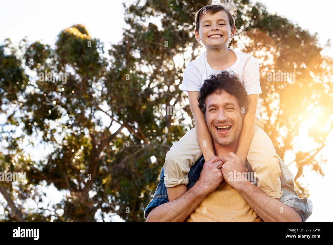 Assicurarsi che il suo ragazzo è divertente. Ritratto di un padre felice che porta il figlio piccolo sulle spalle all'aperto. Foto Stock
