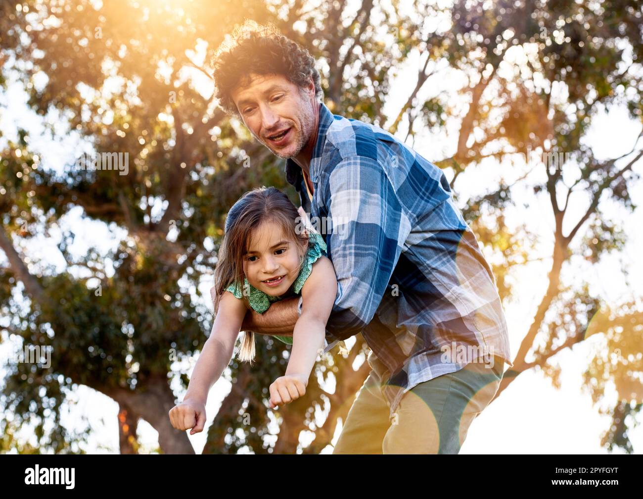 Sei pronto per il decollo? un padre che trasporta giocosamente sua figlia durante una giornata di divertimento all'aperto. Foto Stock