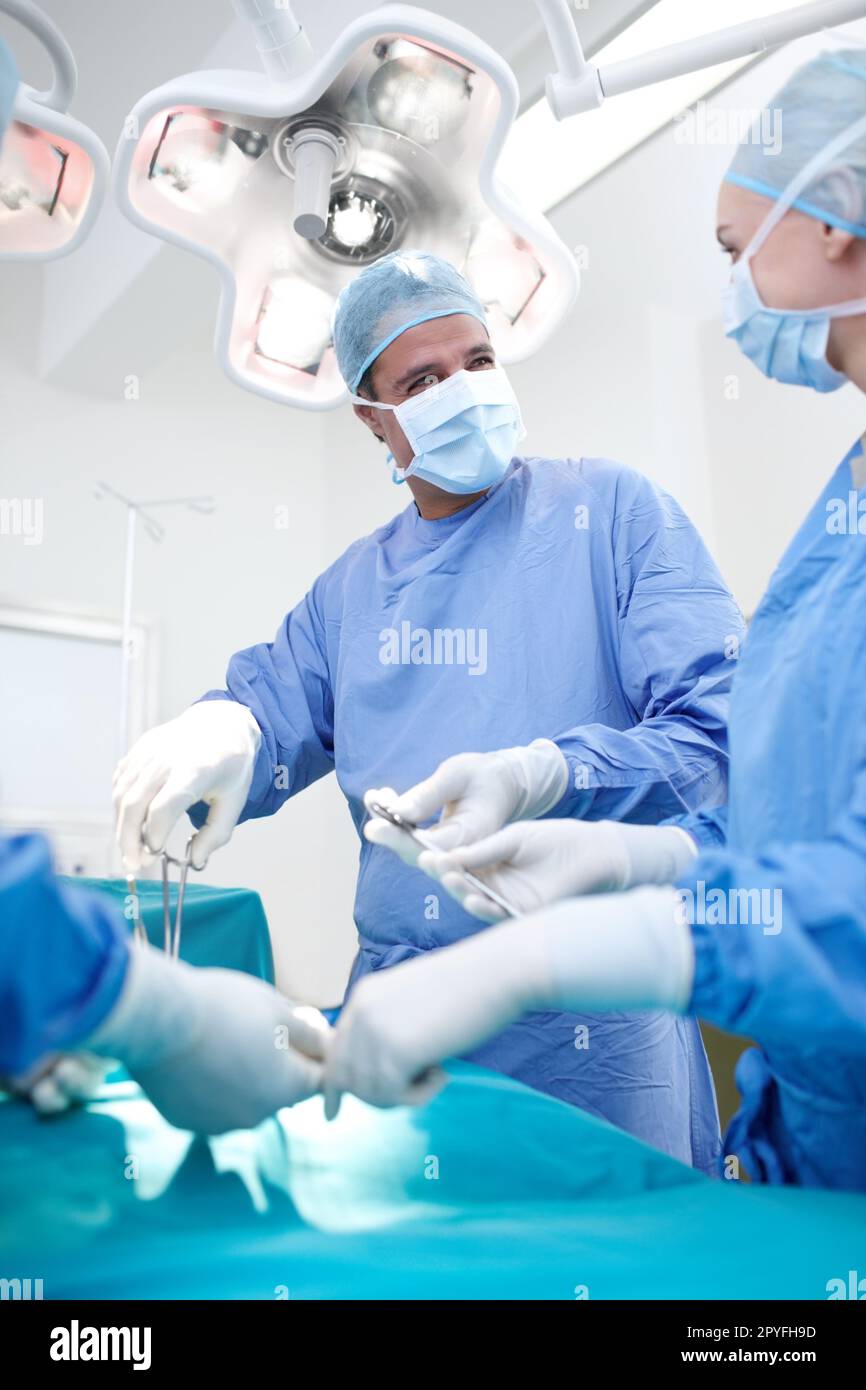 Contribuire a salvare vite quotidiane. Infermiera femminile che assiste un medico di sesso maschile durante un intervento chirurgico. Foto Stock