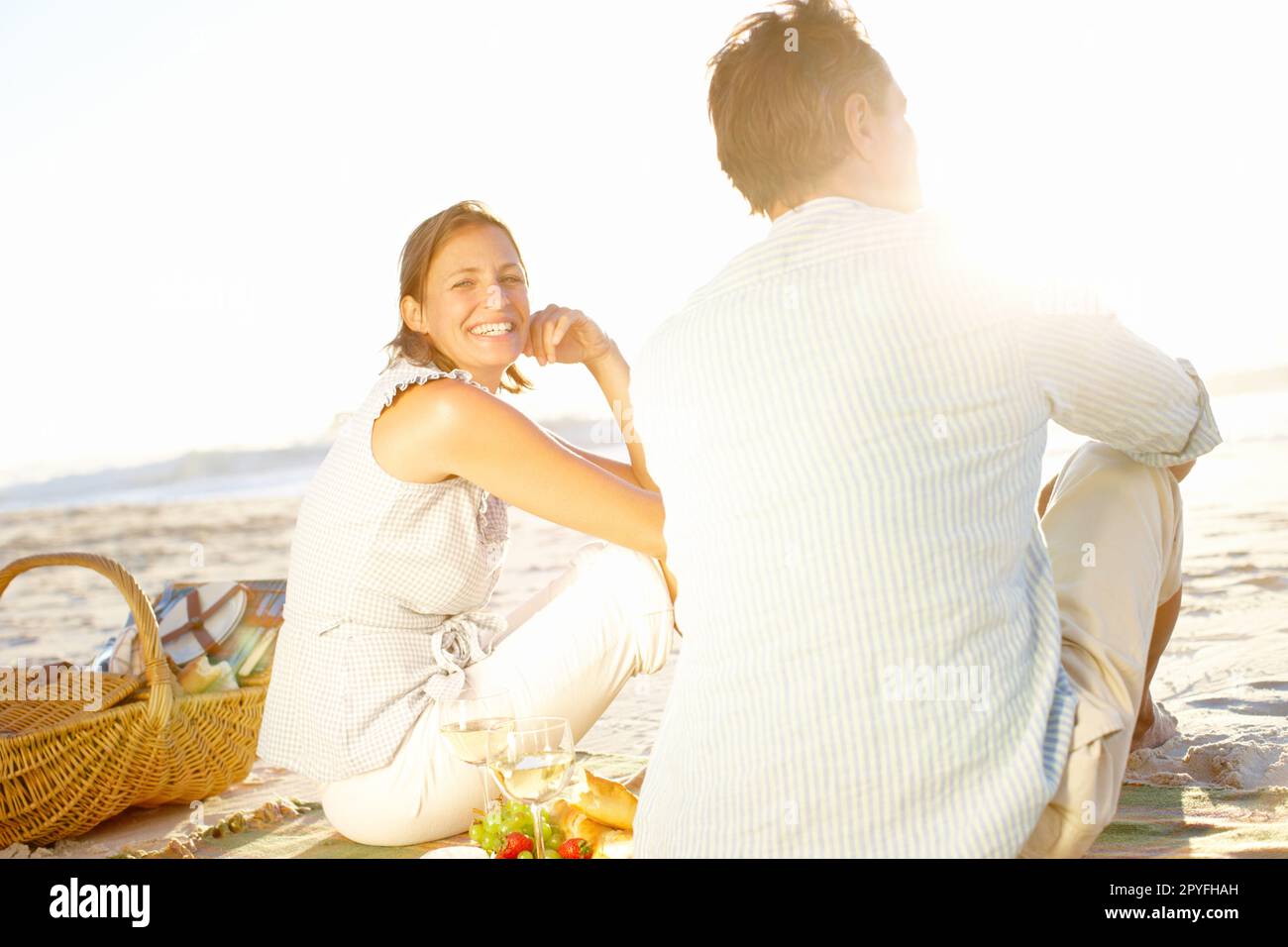 La vita non è mai stata migliore. Una coppia amorevole che guarda il tramonto mentre si gode un picnic insieme sulla spiaggia. Foto Stock