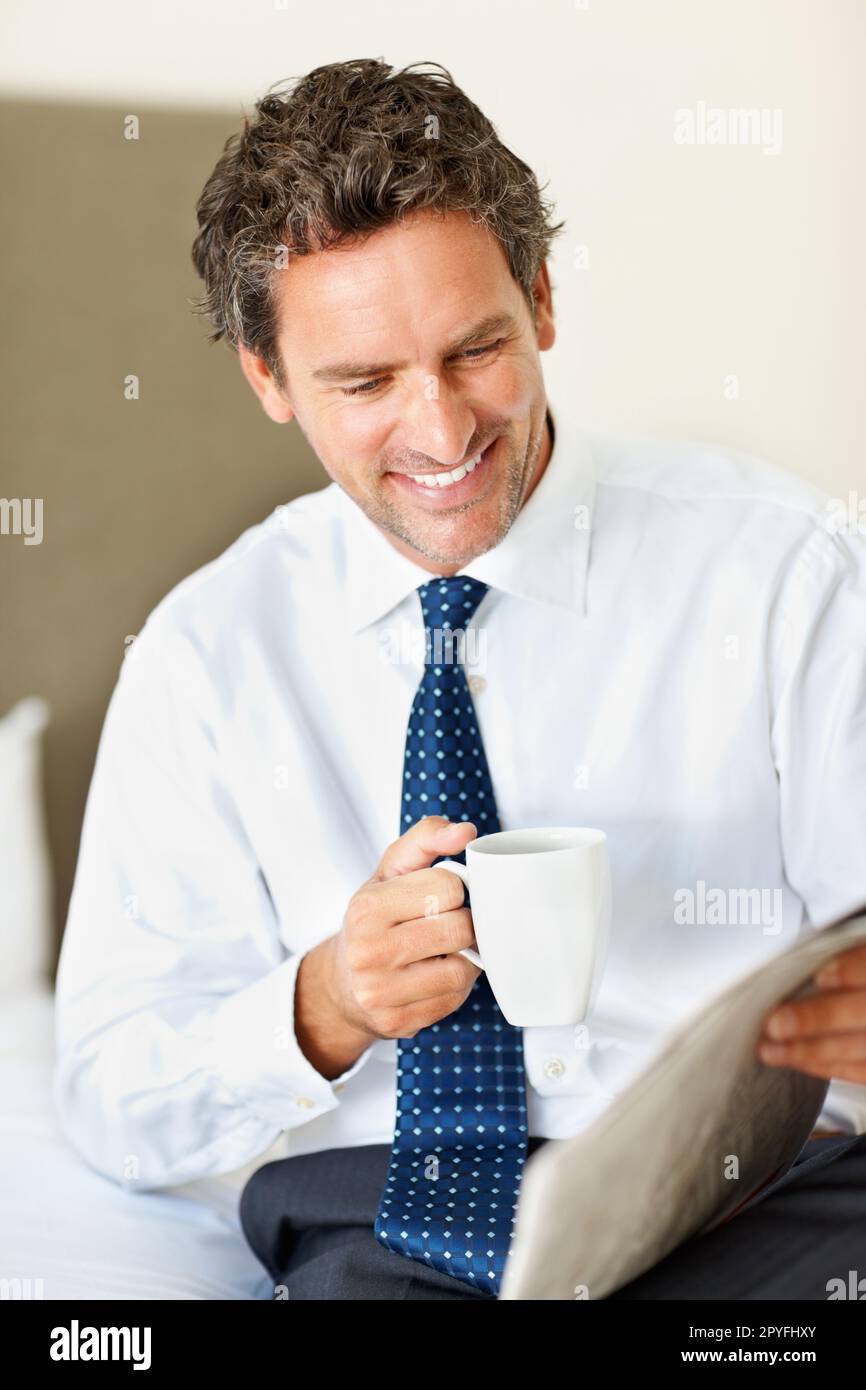Caffè e quotidiano. Uomo d'affari sorridente e intelligente che tiene una tazza di caffè e legge il giornale. Foto Stock