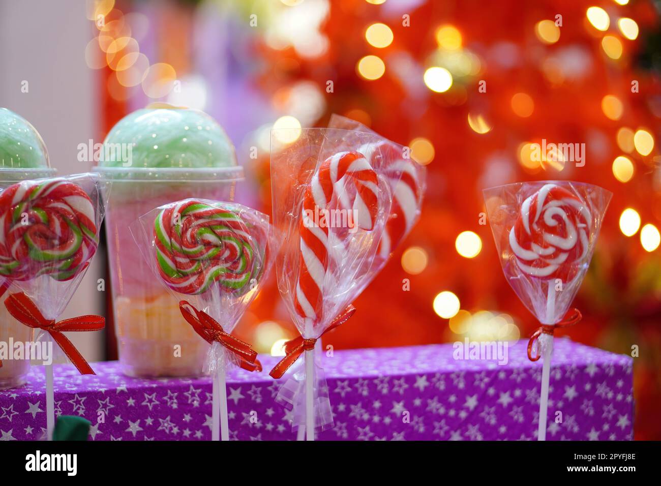 Caramelle natalizie rosse e bianche e lecca-lecca con sfondo rosso sfocato Foto Stock