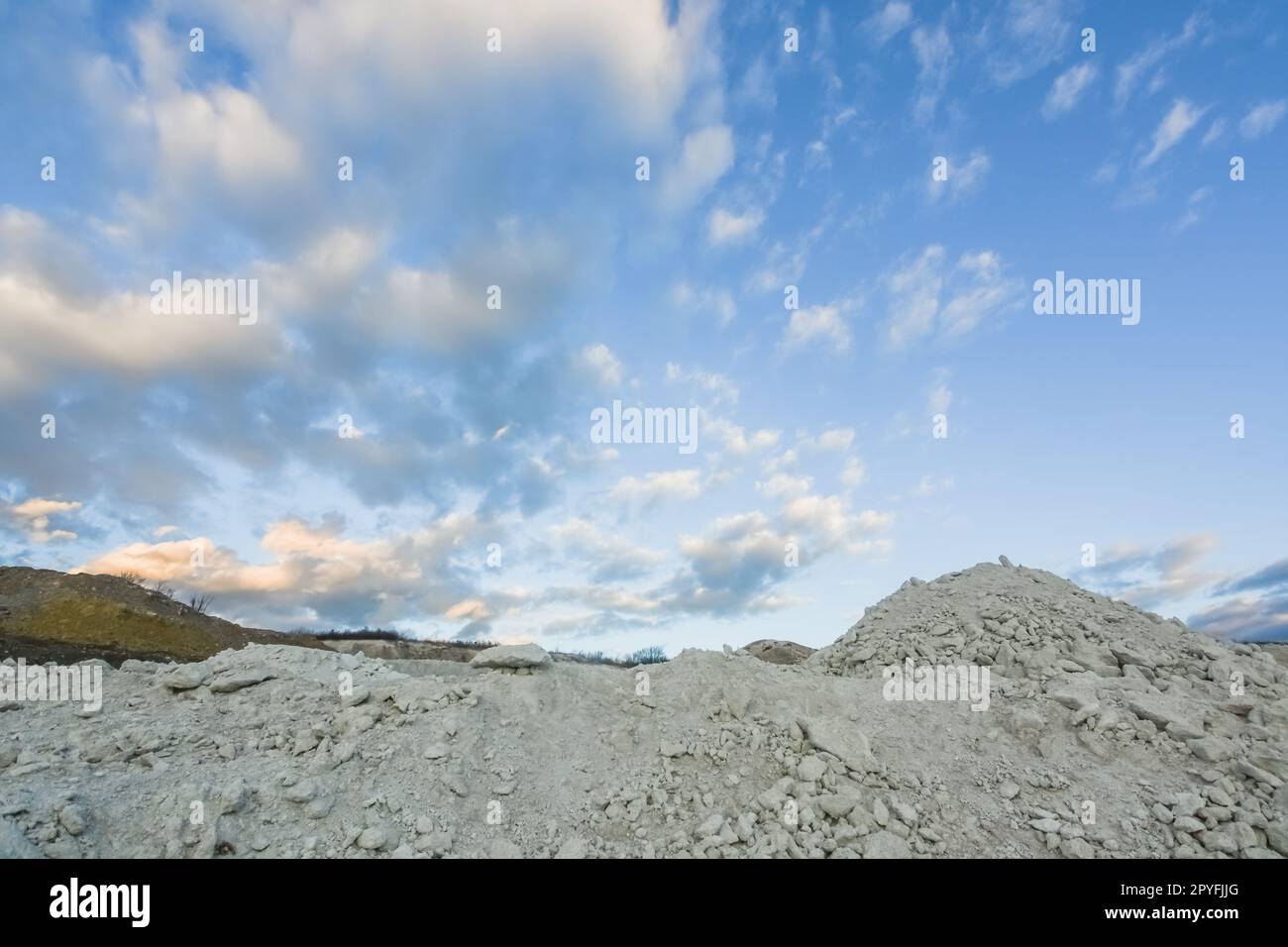 rocce bianche e colline provenienti da una cava di calce con soffici nubi bianche Foto Stock