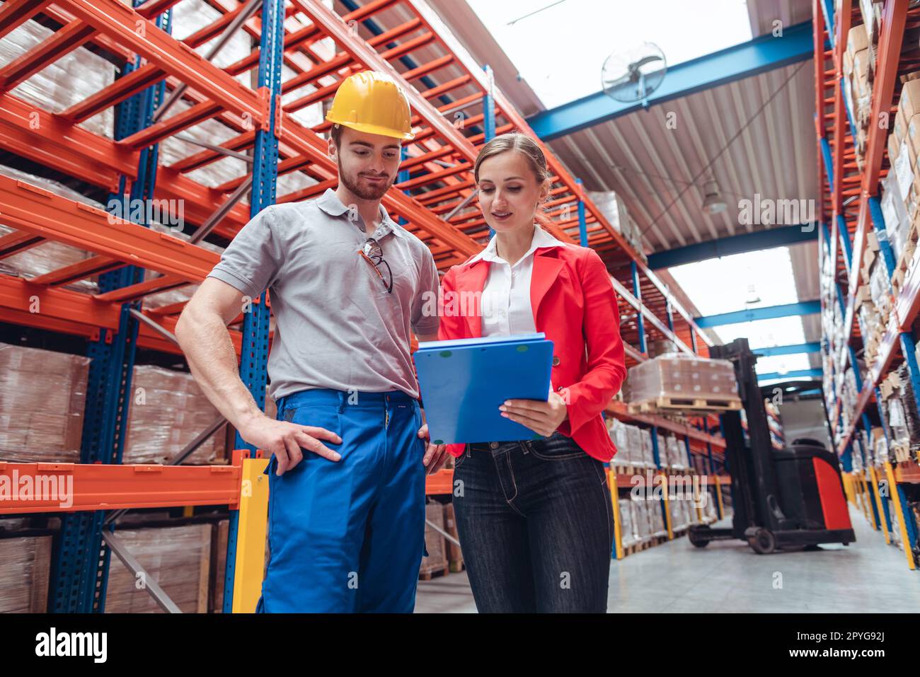 Manager e lavoratore in un magazzino ad alta quota che discute di affari Foto Stock