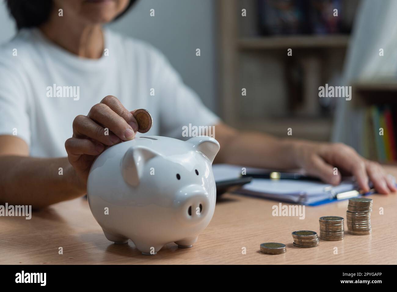 donna che mette la moneta in piggy bank e risparmiare denaro per il futuro piano e fondo pensionistico guadagnare denaro o investimento o tassa per il concetto di business. Foto Stock