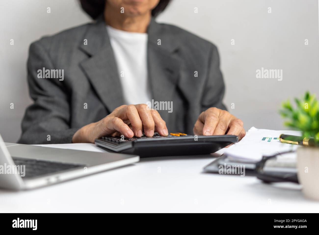 Donna che utilizza calcolatrice e computer portatile sulla scrivania circa il costo a casa Office.Business investimento finanziamento contabilità bancario fiscale concetto. Foto Stock