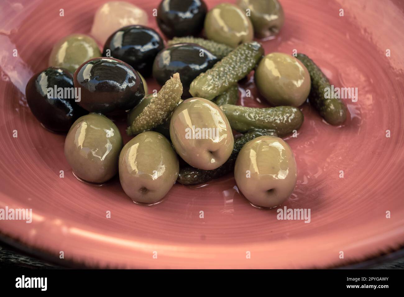 Primo piano di mix di olive nere e verdi con sottaceto in un recipiente arancione. Foto Stock