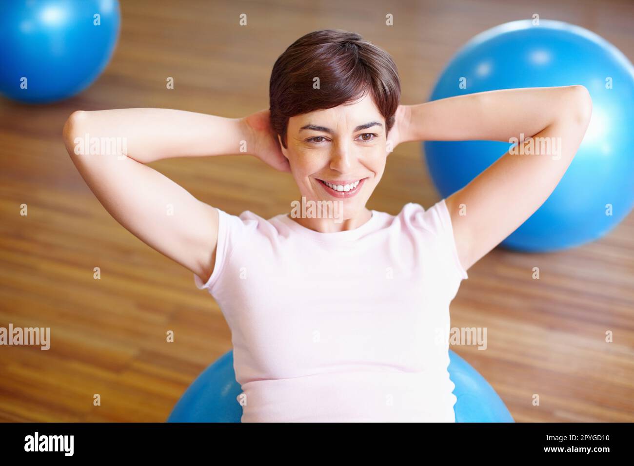 Donna che fa sedersi su palla sportiva. Donna sorridente usando la sfera di sport e facendo sedersi in su durante il suo workout. Foto Stock