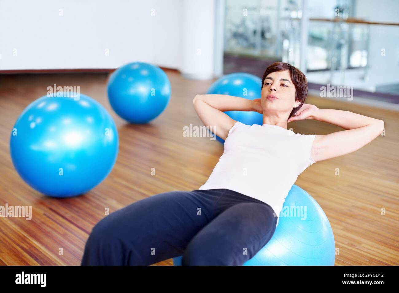 Siediti e allenati. Donna che fa sedersi in su usando la sfera di idoneità in una palestra. Foto Stock