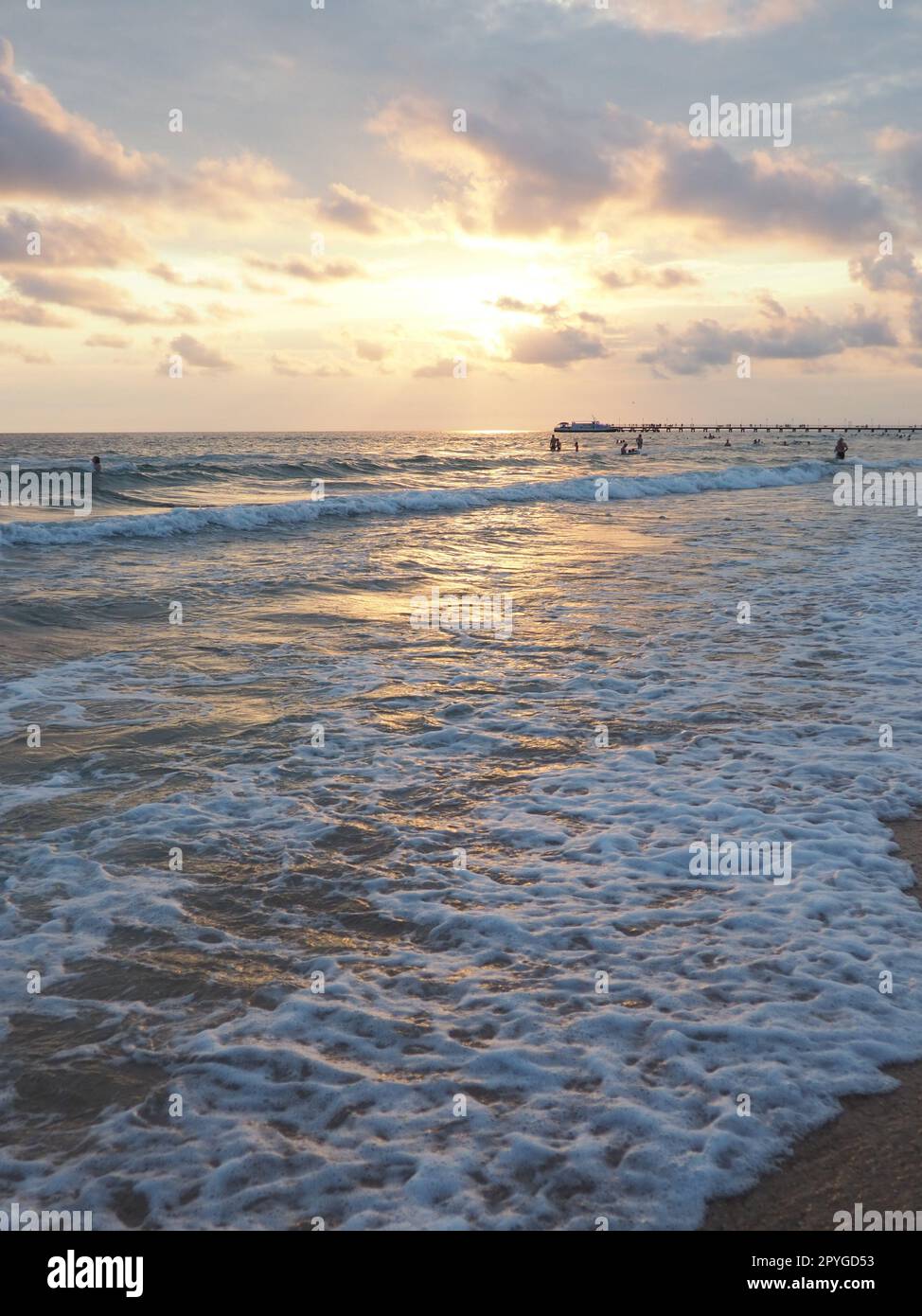 Onde e tramonti sul mare. Bel tramonto. Le onde schiumose si infrangono sulla spiaggia sabbiosa. Vityazevo, Anapa, Mar Nero. Mecca turistica, centro benessere. Cielo serale. I raggi si riflettono sull'acqua. Foto Stock