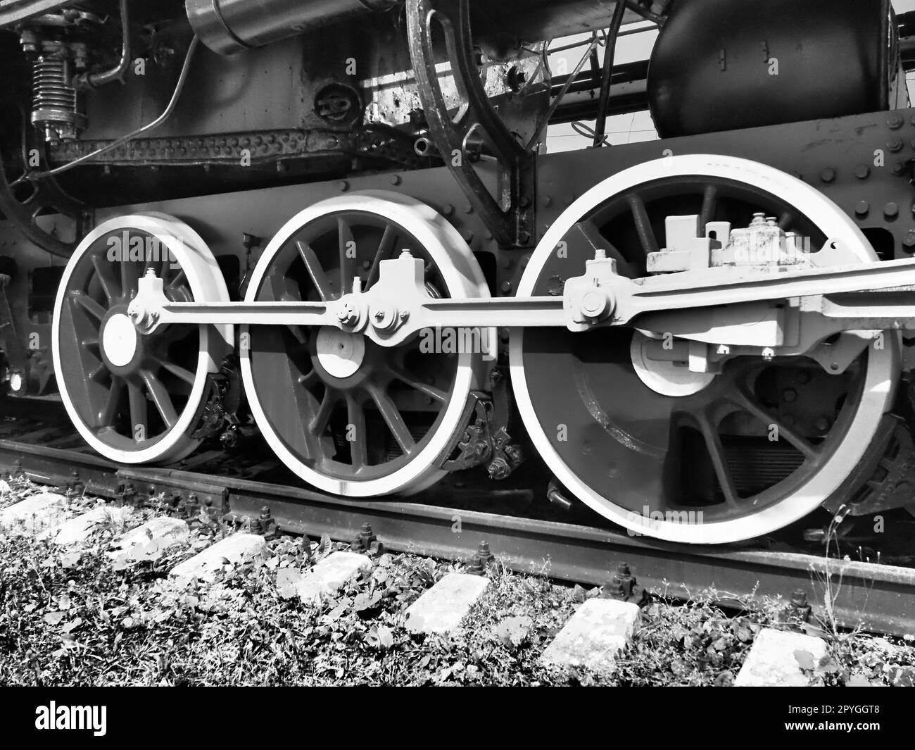 Treno retrò a tre ruote. Traverse e rotaie, meccanismi, pistoni e guide. Locomotiva del XIX secolo all'inizio del XX secolo con motore a vapore. Stile vintage. Foto in bianco e nero. Bella carta. Foto Stock