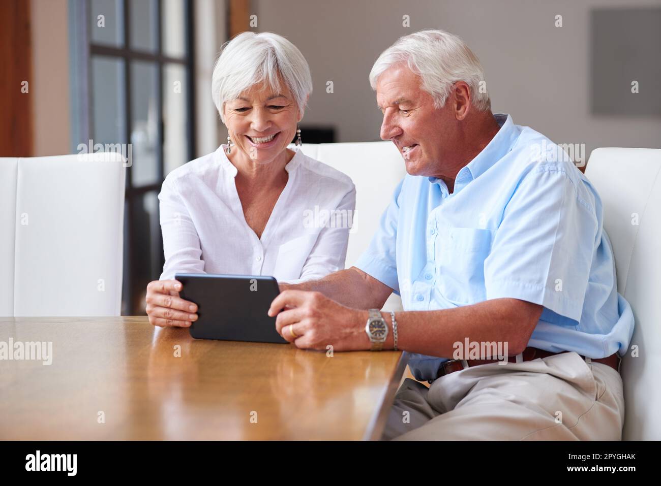 Grazie alla tecnologia sono disponibili molte più informazioni. una coppia senior che utilizza un tablet digitale a casa. Foto Stock