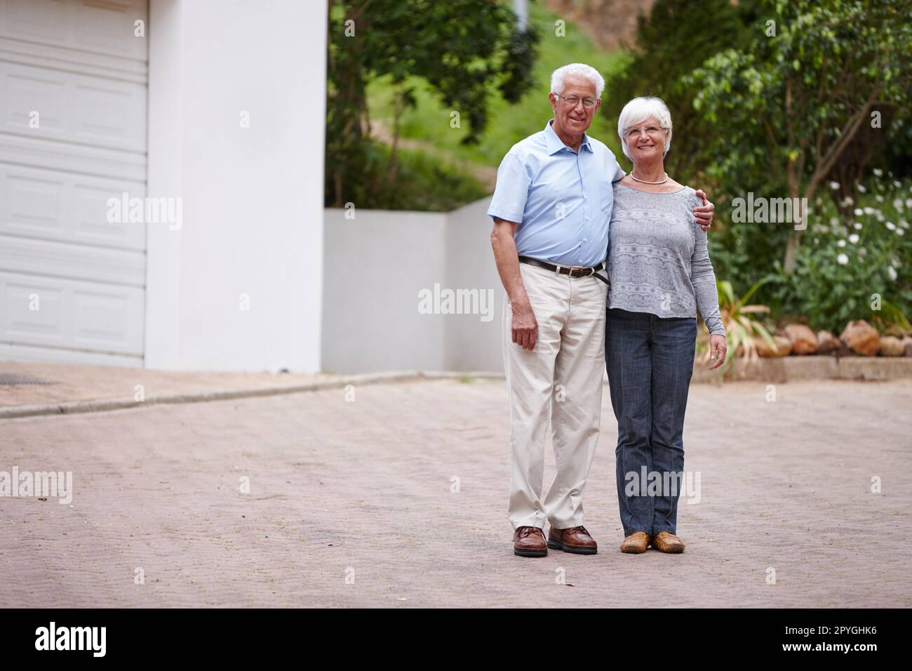 Nelle mie braccia solo per un momento, ma nel mio cuore per sempre. una coppia anziana felice in piedi all'aperto mentre sorride alla macchina fotografica. Foto Stock