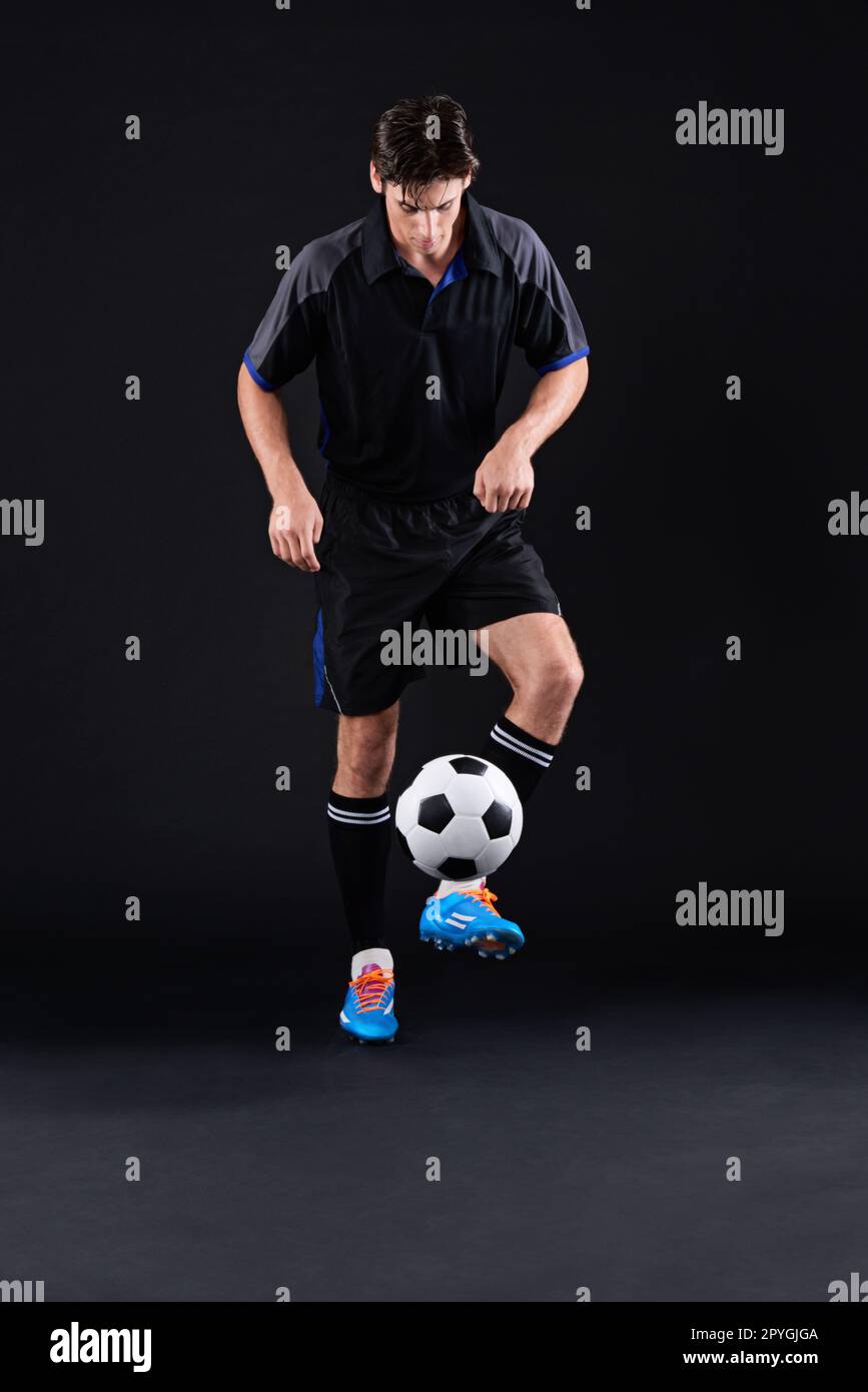 HES andando per quell'obiettivo. un bel giocatore di calcio isolato su nero. Foto Stock