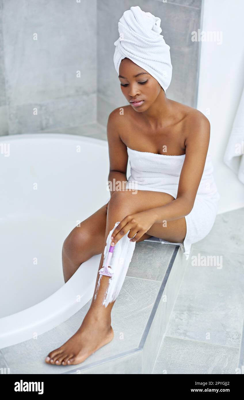 Per un maggiore comfort. Scatto ad angolo alto di una giovane donna che radeva le gambe da una vasca da bagno. Foto Stock