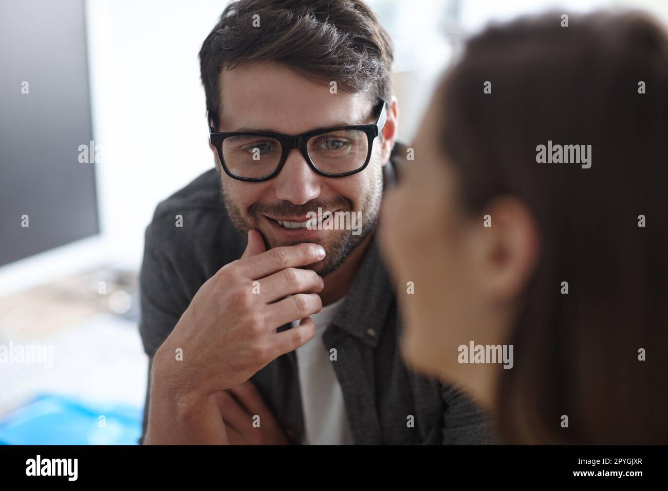 Fate attenzione all'attacco di sneak romantico in ufficio. un giovane designer che ascolta attentamente un collega. Foto Stock