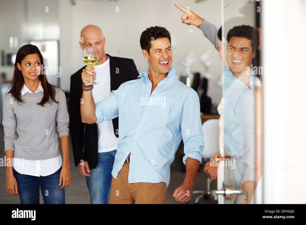 Sviluppare una cattiva reputazione sul posto di lavoro. Un uomo ubriaco con un bicchiere di vino in mano in un ufficio sociale. Foto Stock