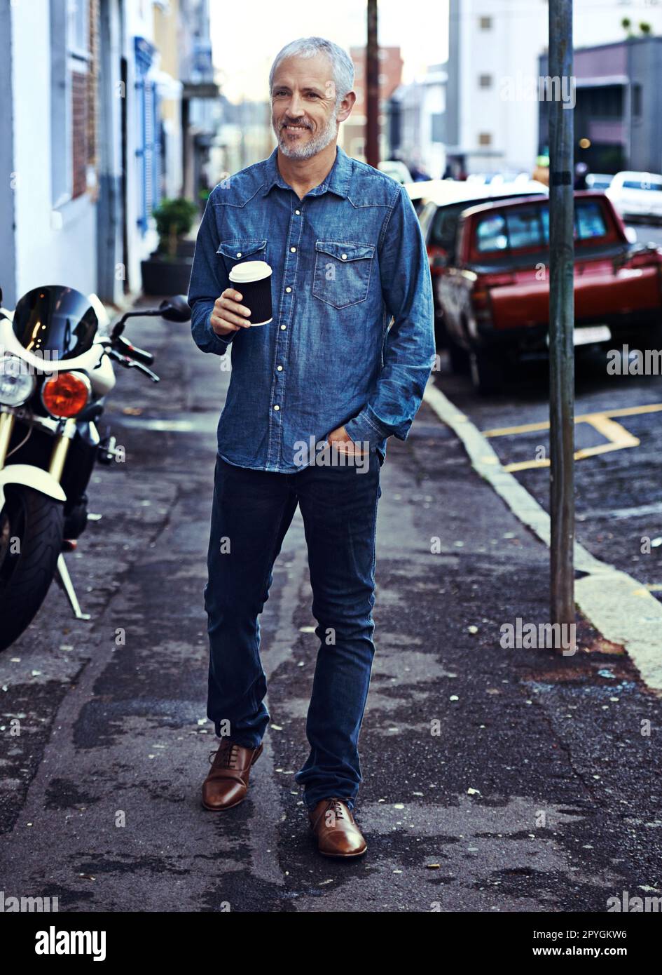 Passeggiando per la città. un bell'uomo maturo che cammina con un caffè da asporto in città. Foto Stock